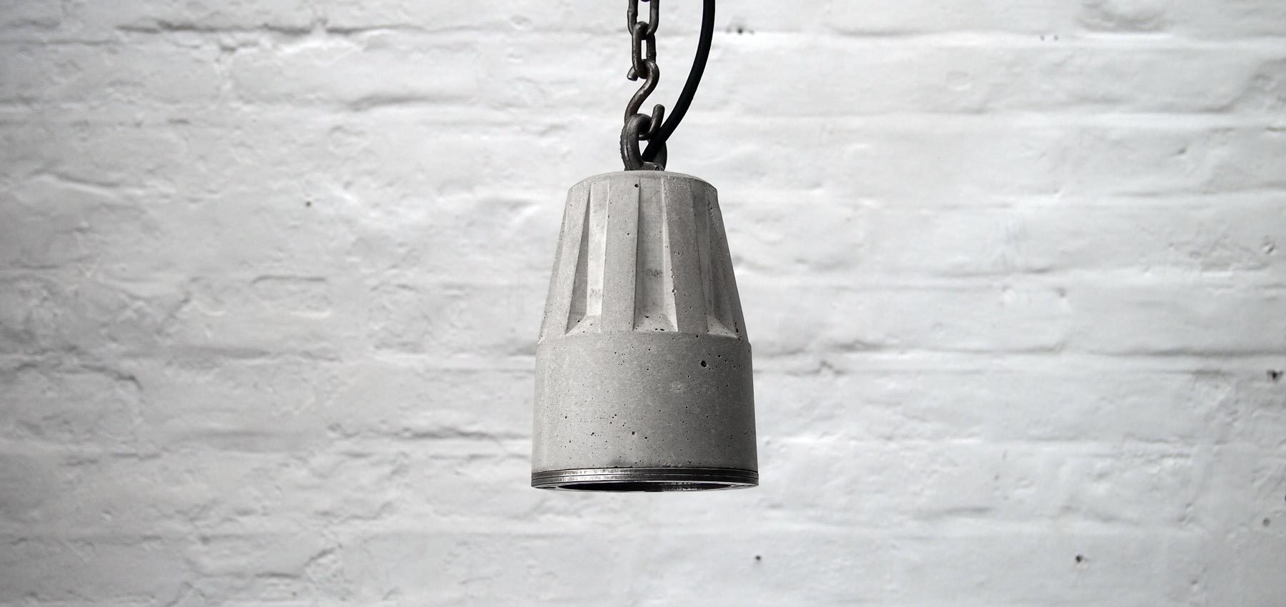 "Concrete pendant lamp with heavy duty hanging chain and steel edging ring" "By Brutal Design"